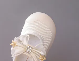 Detailed close-up of girls' Mary Jane shoe with organza bow and rhinestone star accent