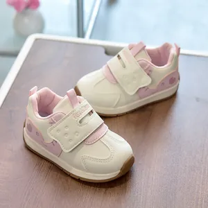 Detailed view of pink and beige kids sneakers with heart pattern and velcro strap