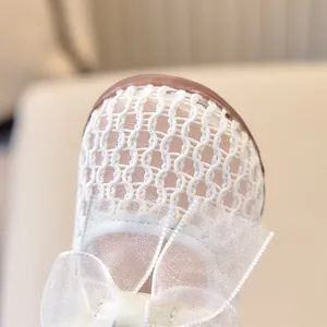 Gros plan de chaussures bébé fille en maille respirante avec un grand nœud en dentelle