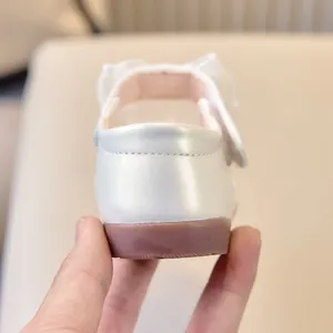 Gros plan sur la chaussure Mary Jane blanc perle avec nœud en maille et semelle souple