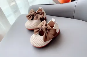 Detail of baby girl shoes with cream knit fabric and brown silk bow decoration