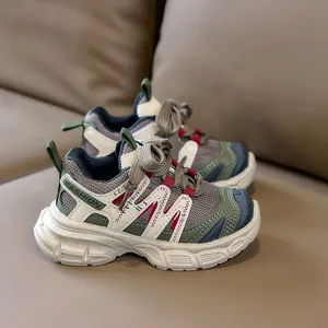 Détail de baskets en maille grise pour enfants avec coutures rouges et étiquette FASHION