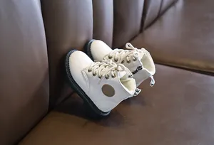 Detail of white kids Martin boots with thick black rubber soles and warm fleece lining