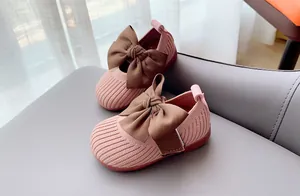 Close-up of pink knit baby shoes with soft soles and large brown satin bow detail
