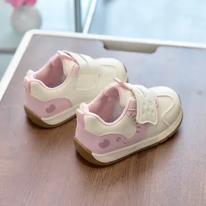Detail of pink and white toddler shoes with cartoon animal motifs and velcro straps