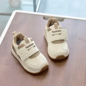 Detail view of toddler beige sneakers with velcro straps and brown accents on wood