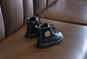 Detail of black matte leather kids boots with side patch and non-slip platform sole