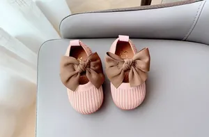 Detailed overhead view of pink knit toddler shoes with brown satin bow and non-slip sole