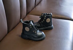 Detail of black leather children's boots featuring side zipper and non-slip rubber soles