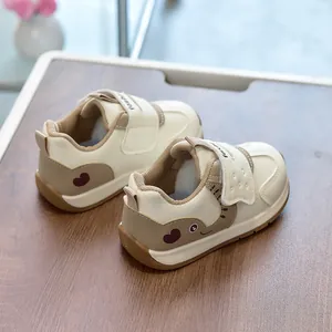 Detailed view of beige and brown toddler sneakers with cartoon elephant on wood surface