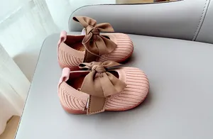 Close-up of pink knit baby shoes with a brown bow and non-slip soft soles