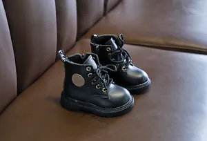 Close-up of kids' black leather boots with lace-up front, zipper side, and chunky soles