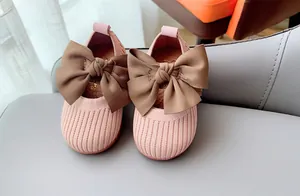 Detail of pink knitted toddler shoes featuring large brown bow and soft ribbed texture
