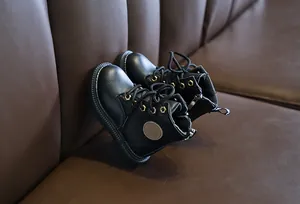 Detail of kids black leather martin boots featuring side zipper and lace-up closure