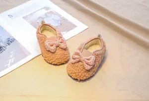 Close-up of baby girl lamb wool shoe with a pink polka dot bow and warm fleece lining