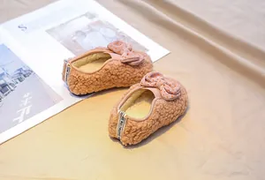 Close-up of brown plush faux fur toddler shoes featuring a cute red polka dot bow detail