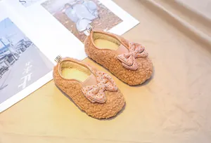 Detailed view of baby faux lamb wool shoes with pink polka dot bow and heel pull tab
