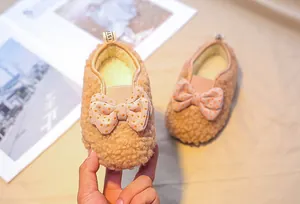 Detail of plush lamb wool baby shoe featuring a pink polka dot bow and warm fleece lining
