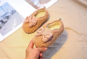 Detail of baby girl fleece shoes in light camel with a pink polka dot bow decoration