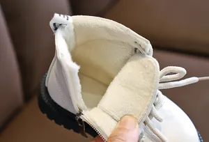 Detailed close-up of warm beige thick faux fur lining and side zipper in white kids boots