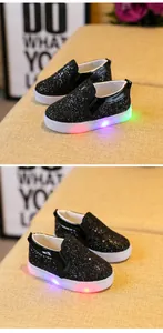 Close-up of kids black glitter LED shoes with glowing RGB lights on white rubber soles