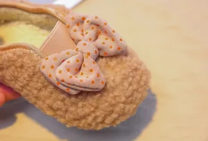 Macro detail of toddler plush fleece loafers featuring a polka dot bow and warm texture