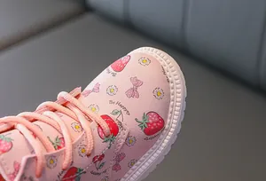 Close-up of pink leather boots featuring strawberry patterns and Be Happy text