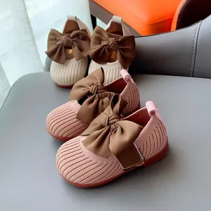Pink and beige knit toddler walking shoes with large satin bows and non-slip soles