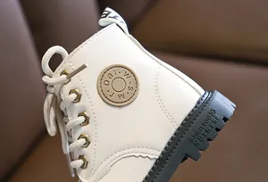 Detail of white leather kids boot showing stitching and golden hexagonal eyelets
