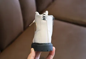 Detail of white leather children boot featuring a side zipper and stylish heel pull tab