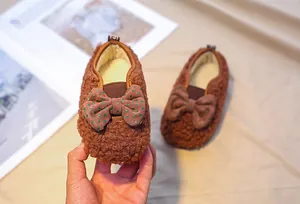Detail of baby plush winter shoes with brown faux fur and a green polka dot bow decoration