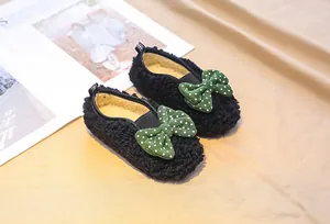 Detail of warm black fleece kids loafers with green polka dot bows and yellow plush lining