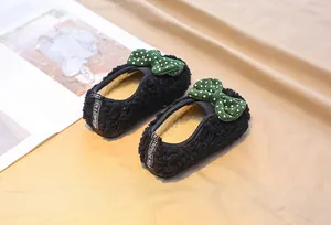 Close-up of black fleece baby shoes with green polka dot bows and warm lining