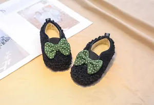 Close-up of girls' black fleece loafers featuring green polka dot bows and plush lining