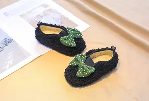 Detail of baby girl fleece shoes with a green polka dot bow and plush warm lining