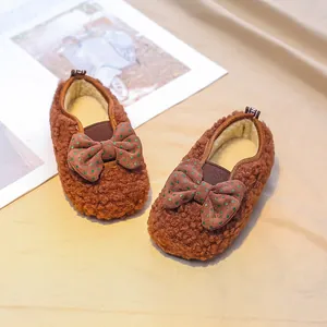 Brown faux lamb wool baby shoes with green polka dot bow and plush lining for winter warmth