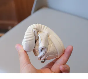 Close-up of flexible cream baby shoes with quilted stitching and soft rubber soles