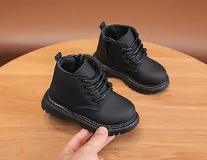 Detail of black children's boots showing side zipper and anti-slip lug sole on wood