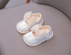 Detail of baby girl Mary Jane shoe with mesh bow, large pearl and shiny patent finish