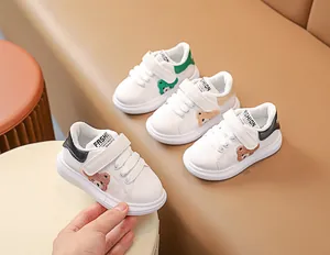 Détail de baskets blanches pour bébé avec écusson ours peluche et velcro