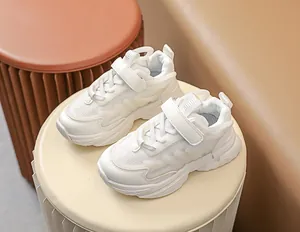 Detail of white kids sneakers with mesh upper, velcro straps and thick cushioned soles