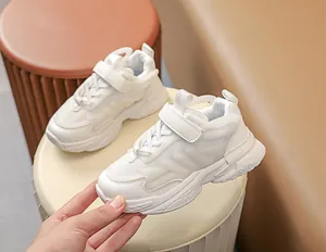 Detail of white kids sneakers featuring breathable mesh, leather panels and velcro strap
