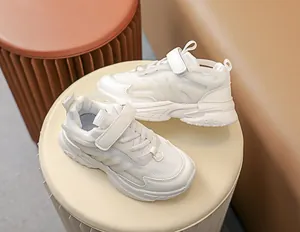Close-up of kids white athletic shoes featuring mesh panels and velcro straps for comfort