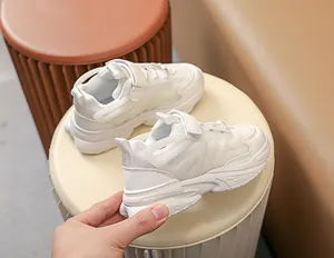 Detail view of white kids' chunky sneakers featuring mesh panels and velcro straps