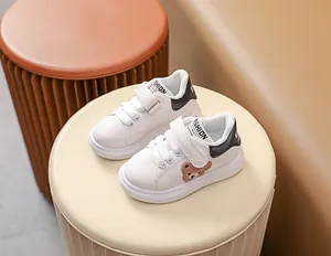 Détail de baskets blanches pour bébé avec broderie ours et attaches velcro