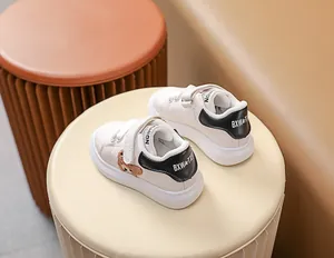 Détail de baskets blanches pour bébés avec broderie ours en peluche et scratchs doubles