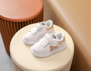 Détail de baskets blanches pour bébés avec velcro et décoration d'ours en peluche