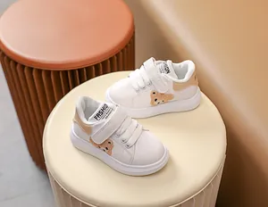 Détail de baskets blanches pour bébé avec motif d'ours en peluche et bride velcro