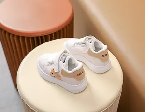 Détail de baskets bébé blanches avec ours en peluche et velcro sur siège texturé