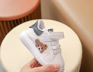 Détail de baskets blanches bébé avec broderie ours en peluche et fermeture velcro